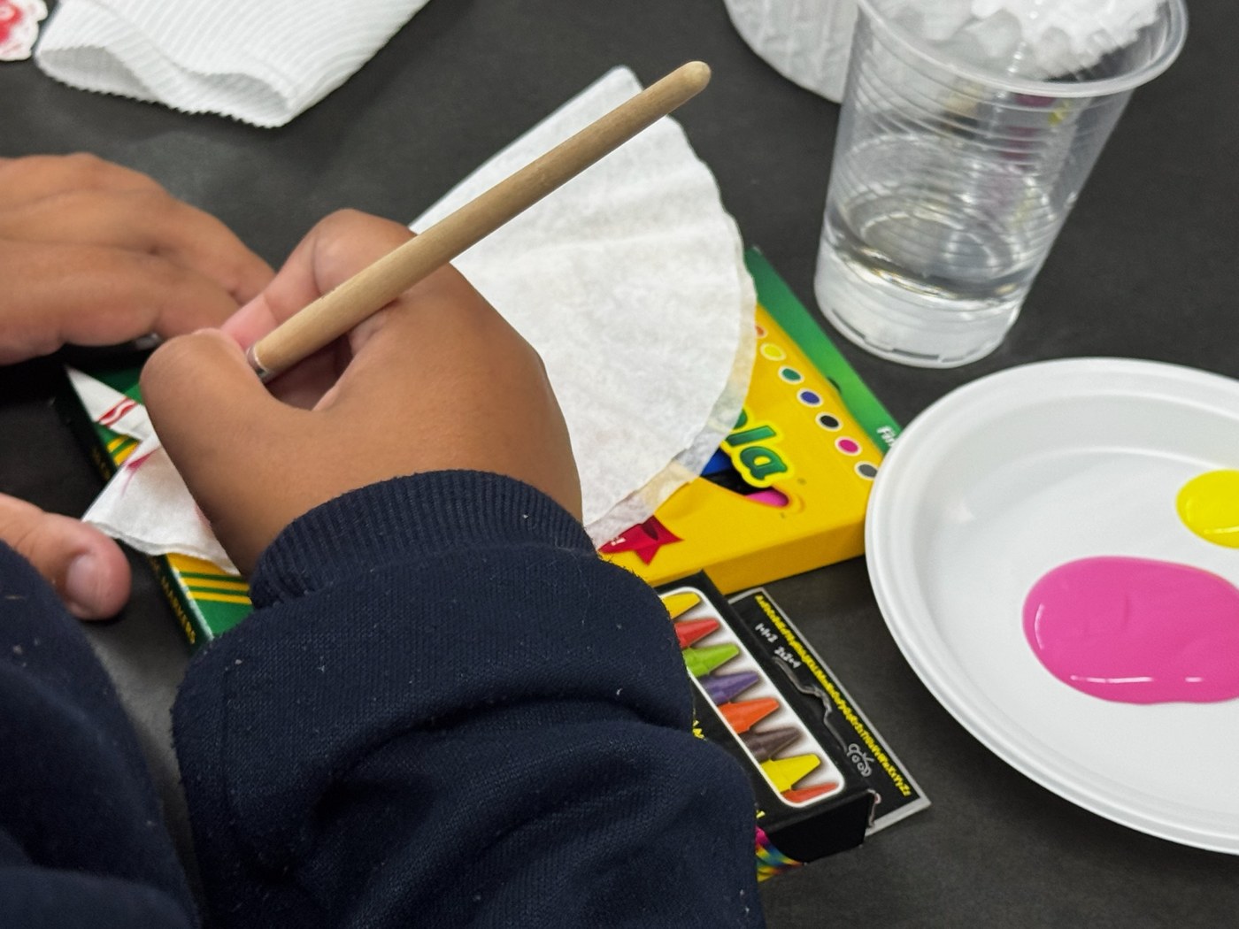 A student’s hands working with paint and paper